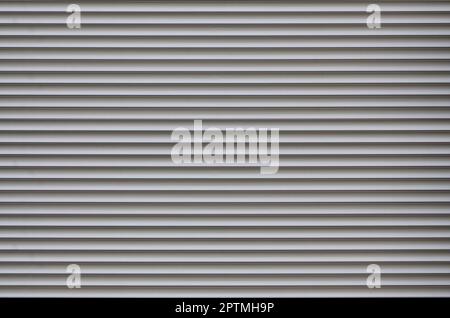 The texture of the shutter door or window in light gray color. Metal gates or shutters for garage or shop, metal sheet texture, steel rolling shutter Stock Photo