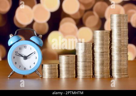 Time for savings money concept, banking and business idea. Alarm clock and Money coin stacks in grow graph. Finance sustainable development and econom Stock Photo