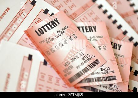 Red lottery ticket lies on pink gambling sheets with numbers for marking to play lottery. Lottery playing concept or gambling addiction. Close up phot Stock Photo