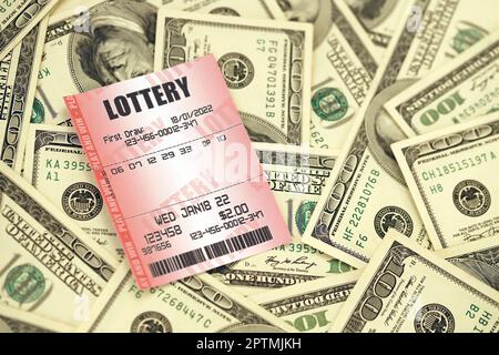 Red lottery ticket lies on big amount of hundred dollar bills. Lottery playing concept or gambling addiction. Close up photo Stock Photo