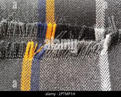 Light black-gray folded fabric with orange and dark blue stripes. Ripped, unfinished fabric edge. Interior decoration. Dress fabrics in casual style. Stock Photo