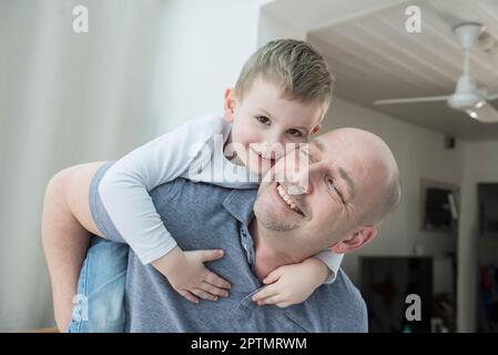 Father carrying son piggyback at home Stock Photo