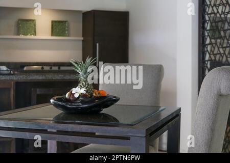 Fruit bowl with a pineapple, oranges, snake fruit and bananas on a wooden table Stock Photo