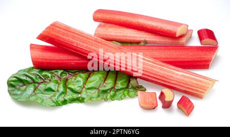 Red rhubarb stems' cuts over rhubarb leaves isolated on white background. Stock Photo