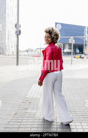 Rear view of  woman in pink jacket walking down the street Stock Photo