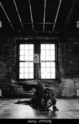 Contemporary female dancer by brick wall in building black and white Stock Photo