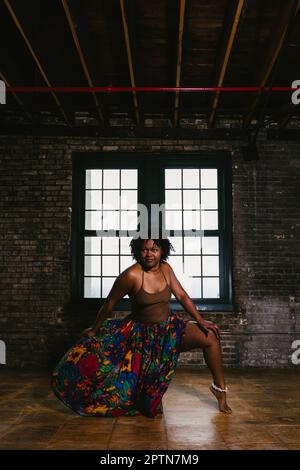 Black woman dancer does pose in front of window in building Stock Photo