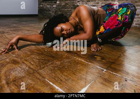 Black contemporary dancer moves on floor in colorful skirt Stock Photo