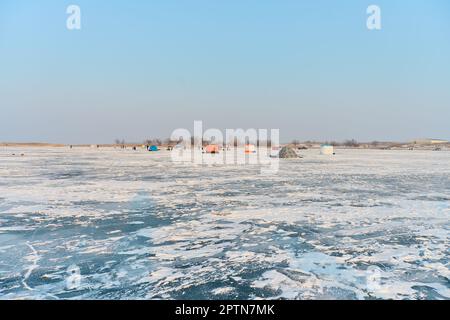 Winter landscape on a frozen lake, people and tents, winter fish Stock Photo