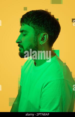 Creative portrait of a bearded middle-aged man. Depressed man with mental problems looking down sadly and falls apart. Colored green light on yellow Stock Photo