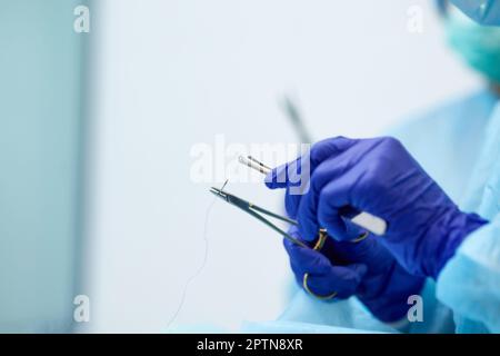 Doctor's, surgeon's hands holding professional medical tools. Doctor wearing protective gloves and apron. Stock Photo