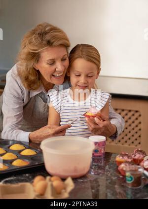 Those look amazing, honey. a little girl decorating cupcakes with the help of her grandmother Stock Photo