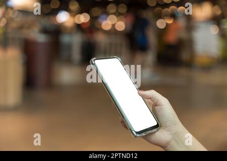Female hand holding smartphone with blank screen on bokeh light background Stock Photo