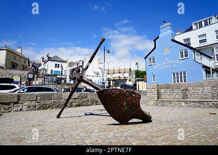 Large anchor displayed along the seafront with The Rock Point Inn and shops to the rear, Lyme Regis, Dorset, UK, Europe. Stock Photo