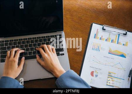 Professional business woman working on laptop computer with chart graphs and calculator on desk in office, top view business woman checking and analys Stock Photo