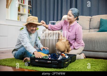 Asian couple old senior marry retired prepare luggage suitcase arranging for travel, Romantic retired couple packing clothes travel bag suitcase toget Stock Photo
