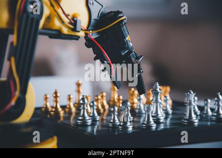 Closeup yellow robot arm playing move chess on chessboard, STEM education E-learning, Technology science robot education concept Stock Photo