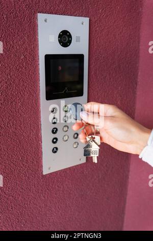 A Young Woman Types The Apartment Code On The Electronic Intercom.