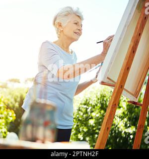 She could paint for days. a senior woman painting in the park. Stock Photo