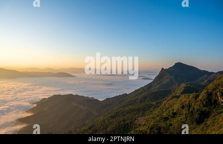 Beautiful landscape on the mountains at sunrise. Spectacular view in foggy valley covered forest under morning sky. Stock Photo