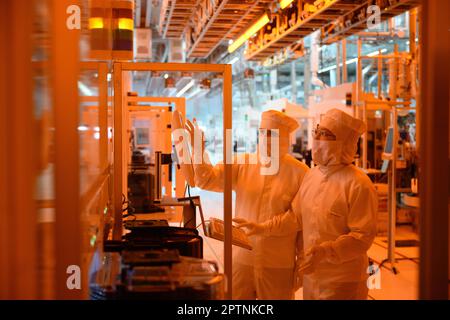 Dresden, Germany. 26th Apr, 2023. Employees of the Infineon chip group work in the clean room of the chip factory. Infineon breaks ground for the new Smart Power Fab in Dresden on May 2, 2023. Credit: Robert Michael/dpa/Alamy Live News Stock Photo