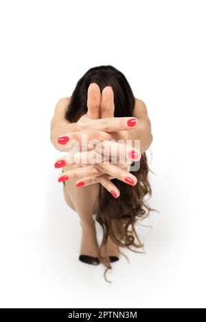 Squatting girl with hands pulled forward and crossed fingers (photo with sahllow depth of field) Stock Photo
