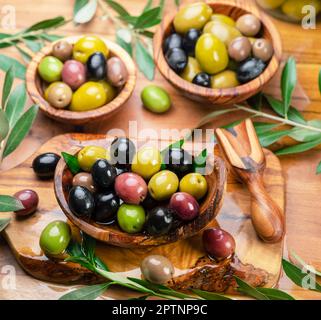 Kalamata, green and black olives in the wooden bowls on wooden table. Top view. Stock Photo