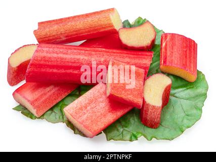 Red rhubarb stems' cuts over rhubarb leaves isolated on white background. Stock Photo