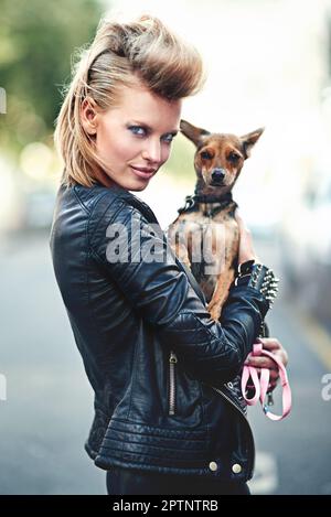 Hes my little rockstar. Cropped portrait of an edgy young woman holding her small dog outdoors Stock Photo