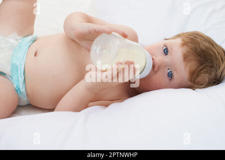 Relaxing with my formula. A sweet little baby lying down drinking a bottle Stock Photo