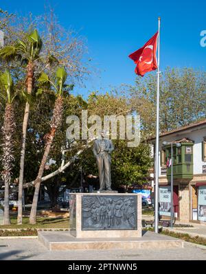 A bronze statue of Mustafa Kamal Ataturk, the founder of modern Turkey stands on a large granite plinth next to a flagpole flying the Turkish flag in Stock Photo