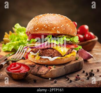 Tasty cheeseburger or hamburger on wooden tray, spices and vegetables near it. Stock Photo