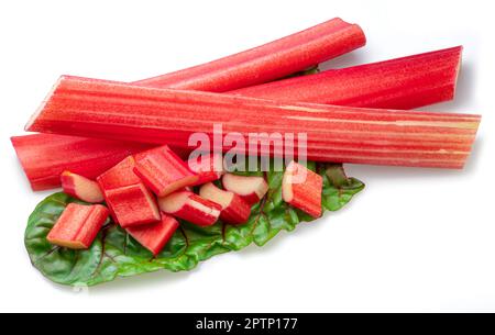 Red rhubarb stems' cuts over rhubarb leaves isolated on white background. Stock Photo