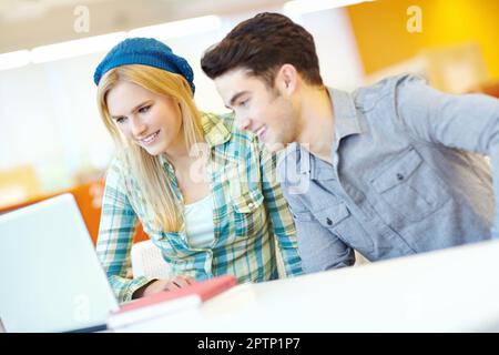 Working together on a class project. Two smiling students helping each other with their homework. Stock Photo