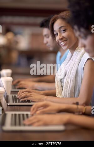 Working towards a bright future. A group of students using a laptop to complete a group assignment Stock Photo