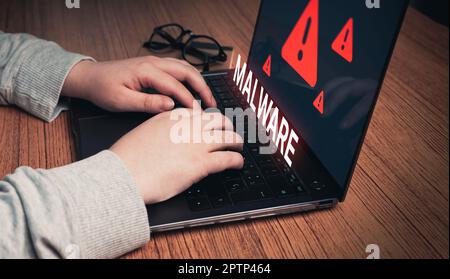Woman using laptop with virtual malware alert. System hacked concept. Cyber attack on computer network, Virus, Spyware, Malware or Malicious software. Stock Photo