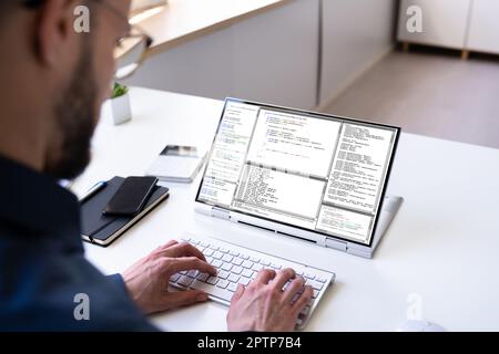 Programmer Or Coder At Office Desk Using Laptop Stock Photo