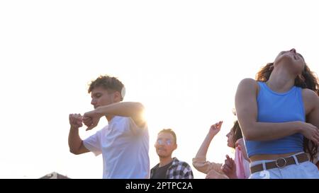 Joyful positive youth dancing at a party during daytime having fun. Males and females dance in good mood. Young people spending nice time together Stock Photo