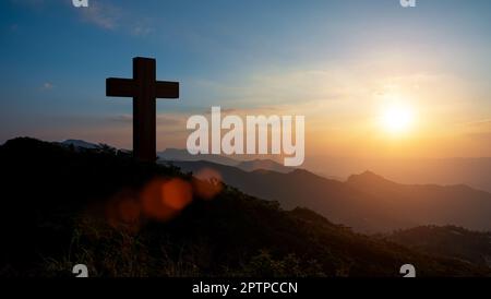 Silhouettes of Christian cross symbol on top mountain at sunrise sky background. Concept of Crucifixion Of Jesus Christ. Stock Photo