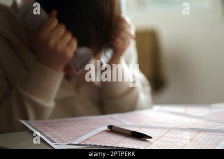 A sad young girl suffers from a loss after looking the unlucky result of the lottery gambling. The concept of losing the lottery and spend money on be Stock Photo