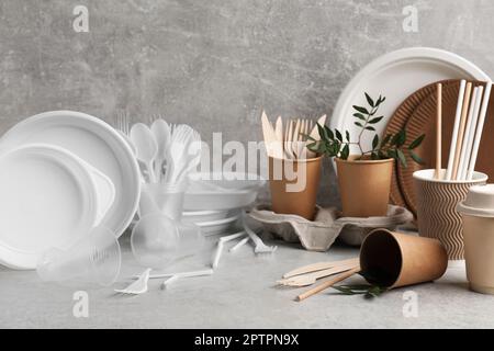 Plastic and eco disposable tableware with green twigs on marble table Stock Photo