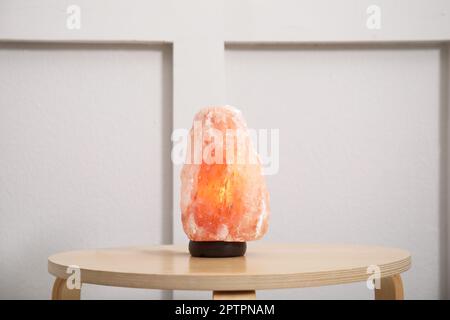 Himalayan salt lamp on wooden table indoors Stock Photo