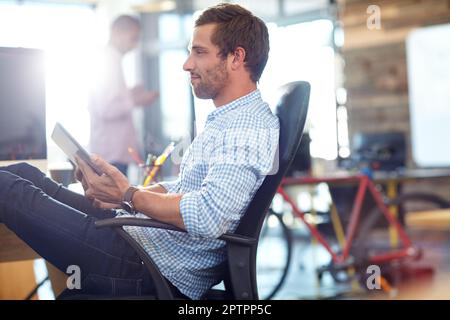 Hes making some progress on his new project. a designer using a digital tablet while working in an office. Stock Photo