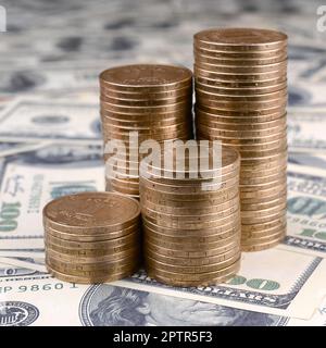Stack of ukrainian coins in rising stacks grow up. Ukrainian money lies on US hundred dollar bills Stock Photo