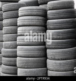 Old used tires stacked with high piles in secondary car parts shop garage close up Stock Photo