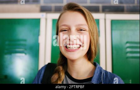 Nothing like a young mind wanting to learn. Portrait of a cheerful young school kid smiling brightly while waiting to go to class inside of a school Stock Photo