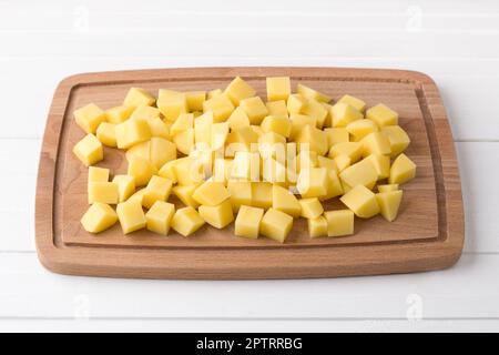Wooden board with fresh diced potatoes on a light gray background. Stage of cooking vegetable stew Stock Photo