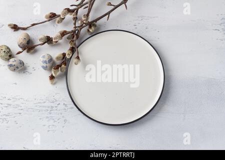 White plate, willow branches, eggs on a light blue background, Easter composition. top view Stock Photo