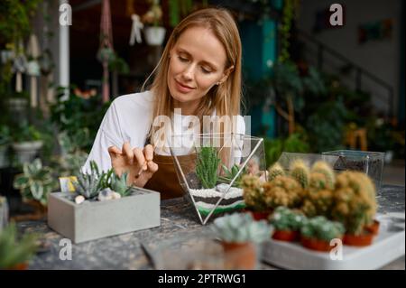 A woman making composition in florarium vase. Happy florist creating succulent plants composition Stock Photo