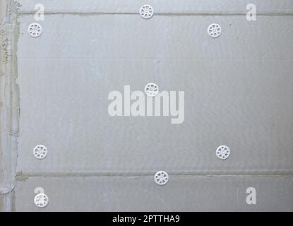 The texture of the wall, covered with gray foam polystyrene plates, which are reinforced with plastic umbrella dowels. Stage of wall insulation Stock Photo